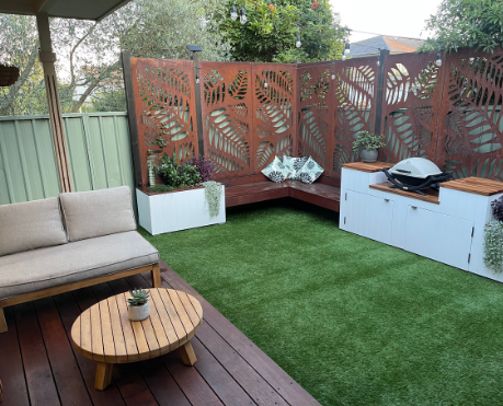 A garden with small deck, metal decorative fence and BBQ area