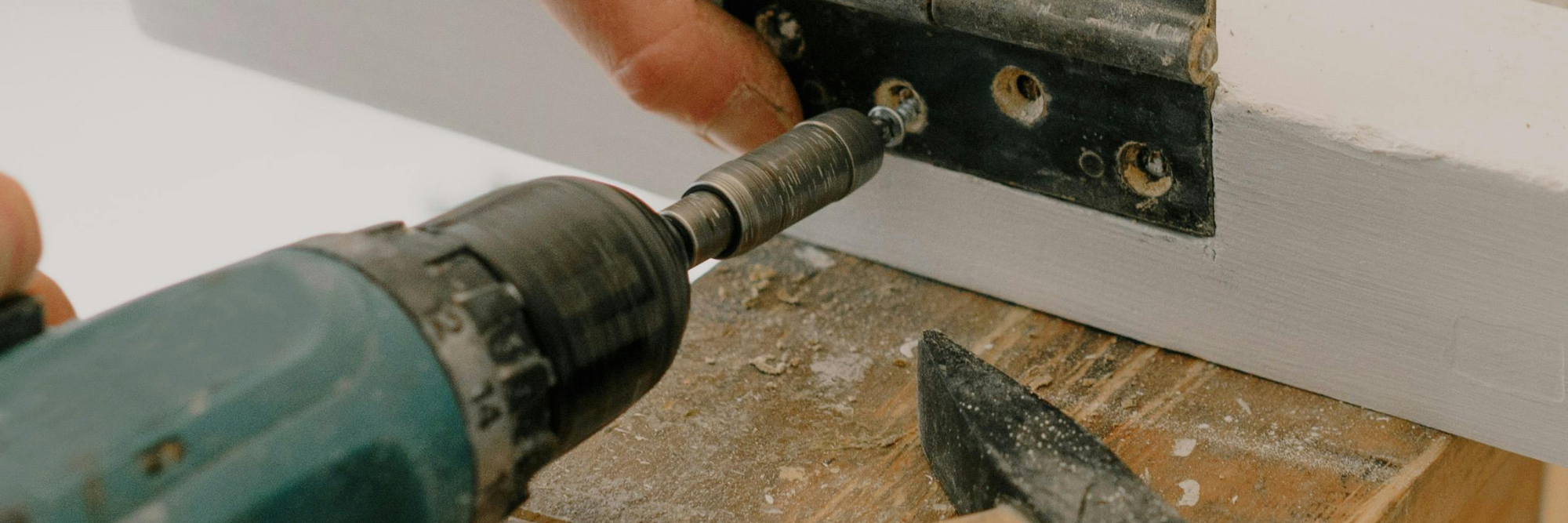 An image of someone drilling a screw into a door fitting